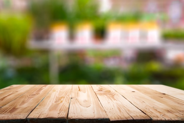 Wooden surface on blurry background of shelving with pots with green flowers