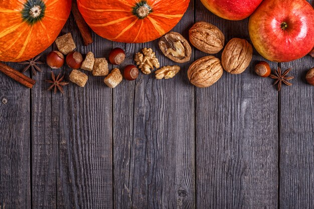 Wooden surface with pumpkin, apples, nuts and spices