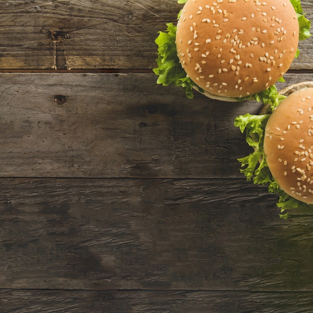 Wooden surface with two burgers and blank space