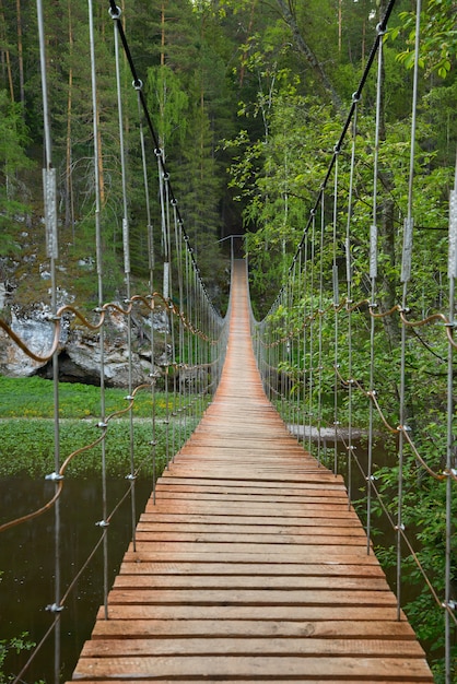 Photo wooden suspension bridge over the river in the forest