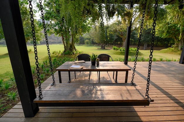 Wooden swing and chair in dining table with green flora on patio