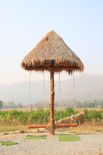 Photo wooden swing hanging under sunshade umbrella in the nature garden