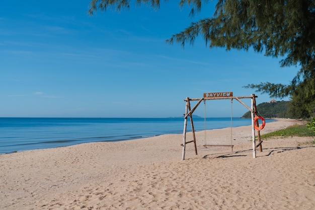 バンクルートビーチの砂浜の木製スイング。タイのプラチュアプキリカーンの旅行先。夏は休暇をリラックスします。穏やかな波の海。