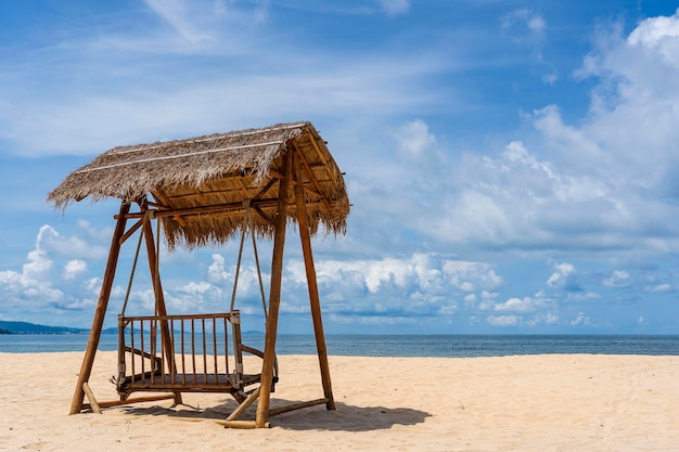 Wooden swing under a thatched roof on a sandy tropical beach near sea on island of Phu Quoc Vietnam Travel and nature concept