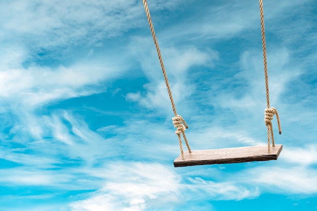 Wooden swing with pastel blue sky and cloud