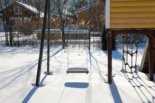 Wooden swing in the yard in winter