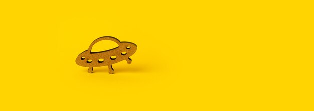 Wooden symbol UFO over yellow background, panoramic mockup