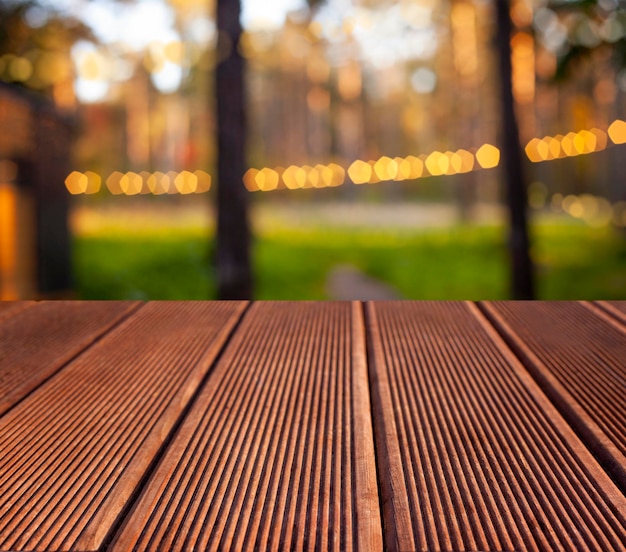 Wooden table background with bokeh defocused lights and trees