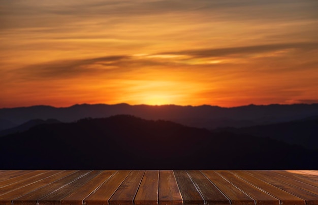 Wooden table and blur of beauty, sunset sky, and mountains as background.