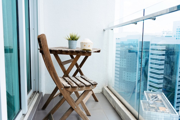 Wooden table and chair on the balcony overlooking the modern big city.