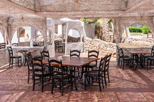 이집트 샤름 엘 셰이크(Sharm el Sheikh)의 홍해 옆 해변 카페에 있는 나무 테이블과 의자가 닫혀 있습니다.