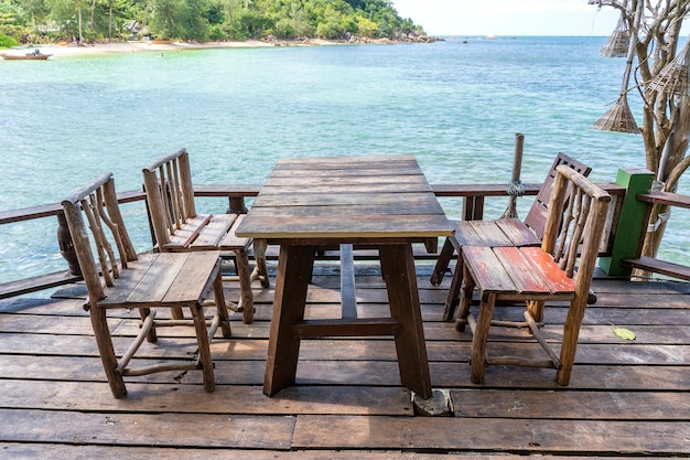 Wooden table and chairs in empty beach cafe next to sea water. Close up. Island Koh Phangan, Thailand