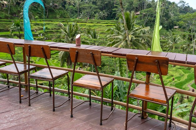インドネシアのバリ島の棚田の隣にある空のトロピカルカフェの木製のテーブルと椅子がクローズアップ