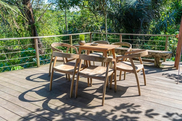 Wooden table and chairs in empty tropical cafe next to rice terraces in island Bali Indonesia