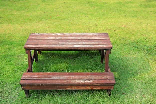 Wooden table and chairs set on green lawn in the garden.