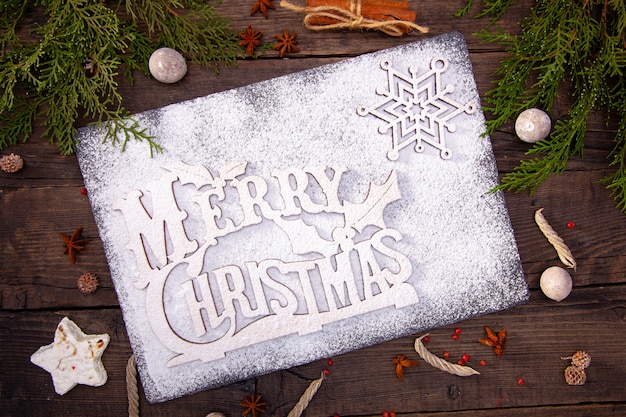 Wooden table, festive sweets, gingerbread, spices, Christmas tree branches, stone board of a happy new year.