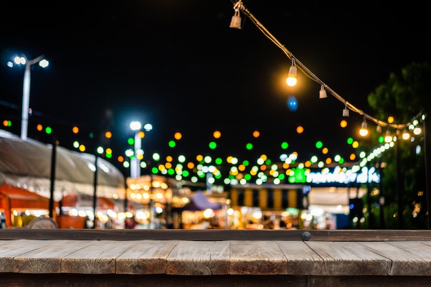 Wooden table in front of decorative outdoor string lights hanging on electricity post.