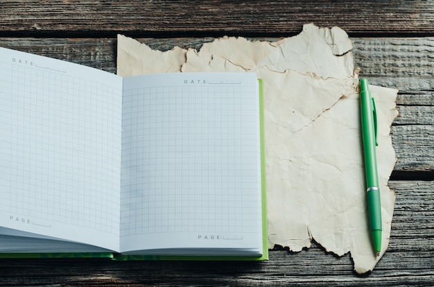 On a wooden table is a notebook, at the bottom of old paper, near the handle