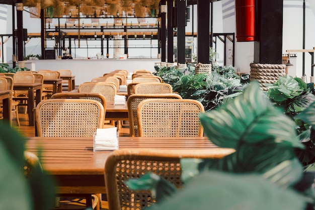 Wooden table and rattan chairs at open cafe outdoor