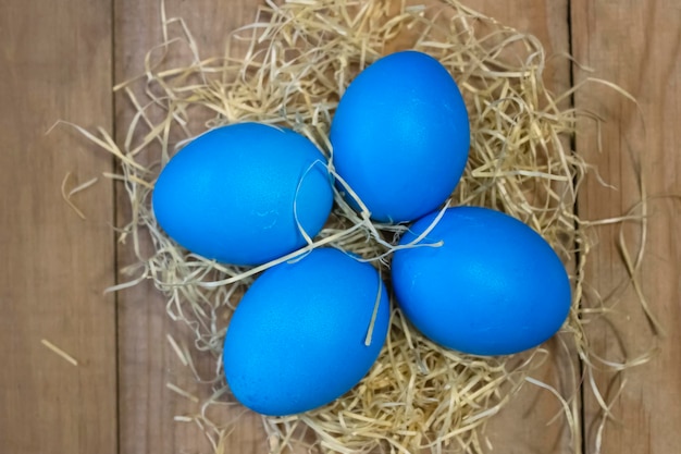 On a wooden table stained Easter eggs in a straw nest Easter and religion concept