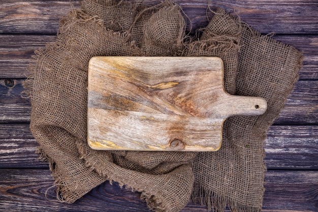 Photo wooden table with burlap cloth and cutting board