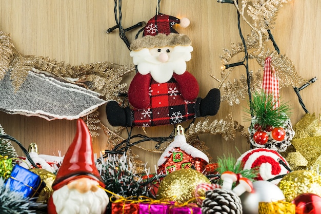 Wooden table with Christmas decorations. Red, silver and gold balls, gift boxes, lights, Santa Claus, Panettone, Christmas tree and others. Selective focus.