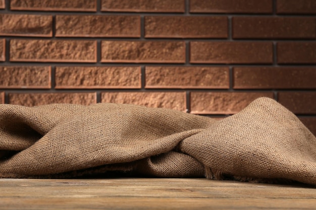 Wooden table with cloth on wall background