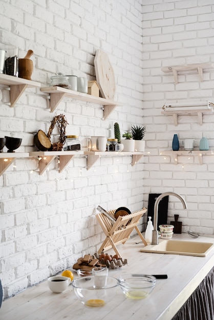 Wooden table with different kitchen utensils on white rustic kitchen pastel colors