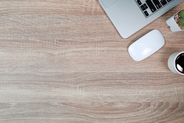 Wooden table with laptop computer and black coffee cup