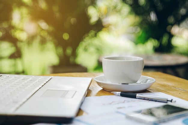 Photo wooden table with laptop smartphone and other supplies with cup of coffee at coffee input the text