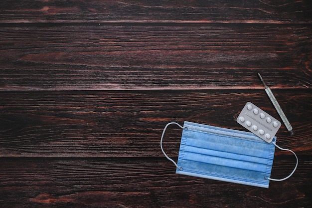 A wooden table with a mask and a pair of pills.