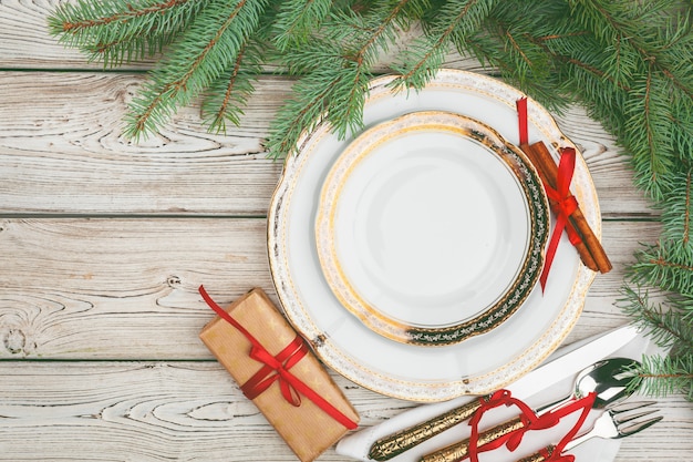 Wooden table with pine tree branches and holiday table setting