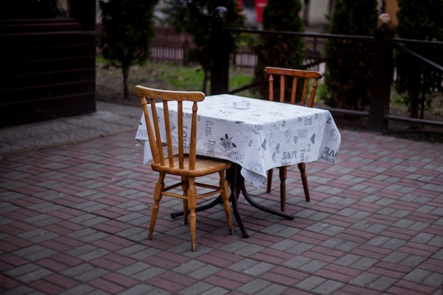 wooden table with a pink tablecloth and chairs on the street. summer terrace cafe restaurant