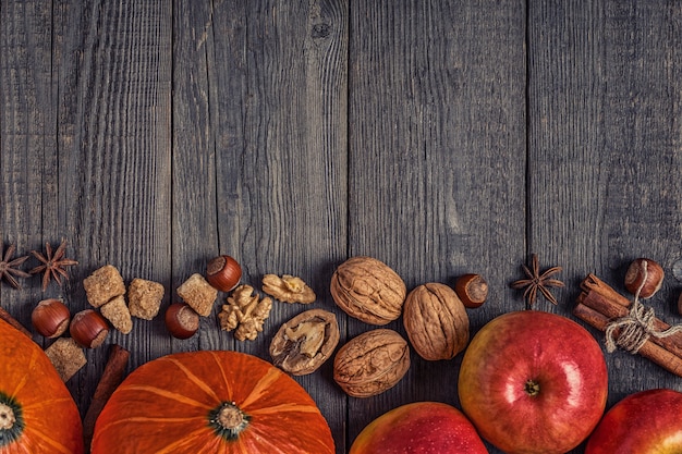 Wooden table with pumpkin, apples, nuts and spices