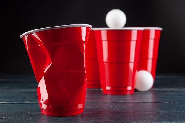 Wooden table with red cups and ball for beer pong