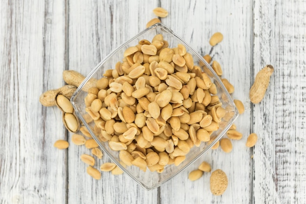 Wooden table with salted and roasted peanuts closeup shot