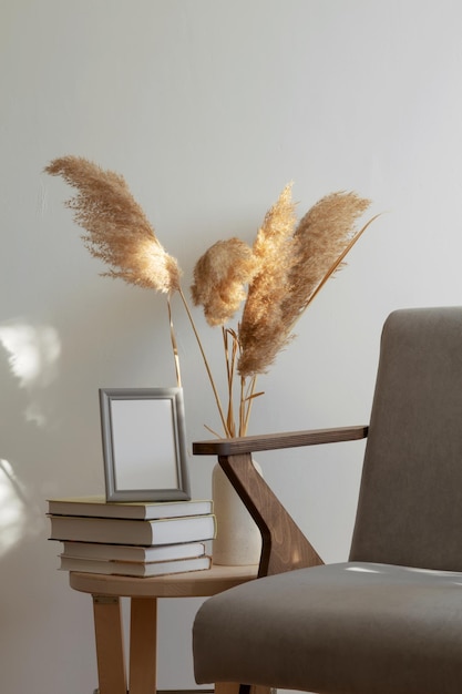 Tavolo in legno con pila di libri e vaso con erba pampas mockup struttura grigia sedia grigia interni scandinavi minimalisti chiari