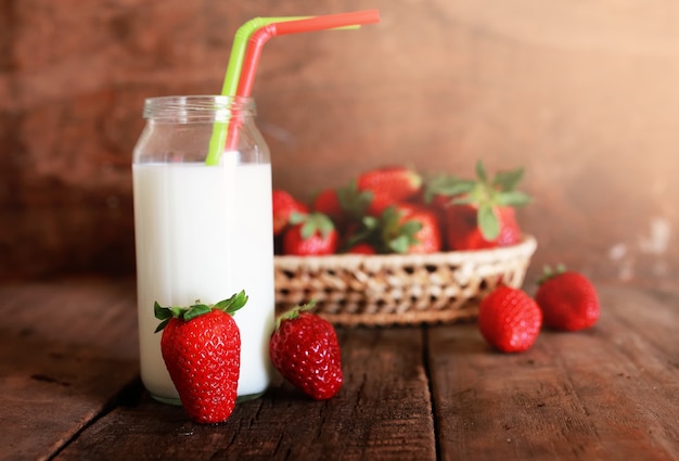 Wooden table with strawberries and milk in a glass