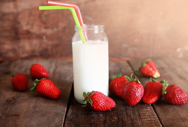 Wooden table with strawberries and milk in a glass