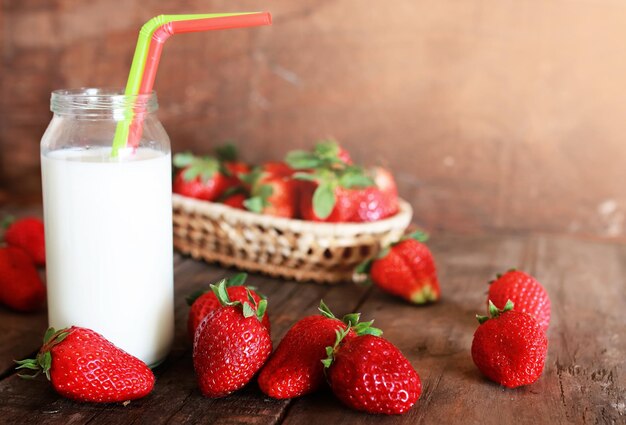 Wooden table with strawberries and milk in a glass