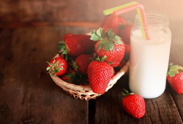 Wooden table with strawberries and milk in a glass