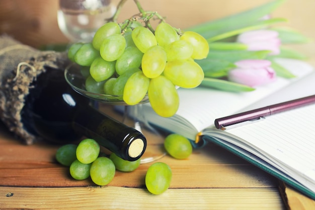 Wooden table with wine bottle book and grape