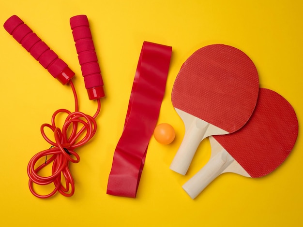 Photo wooden tennis racket for ping pong and a plastic ball on a yellow background