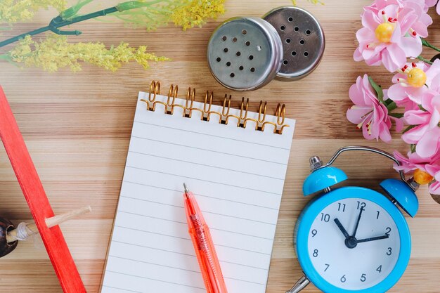 Foto tavolo da ufficio di consistenza in legno con quaderno portatile, penna, quaderno e orologio