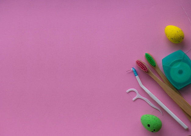 Wooden toothbrushes with Easter decorations on pink background