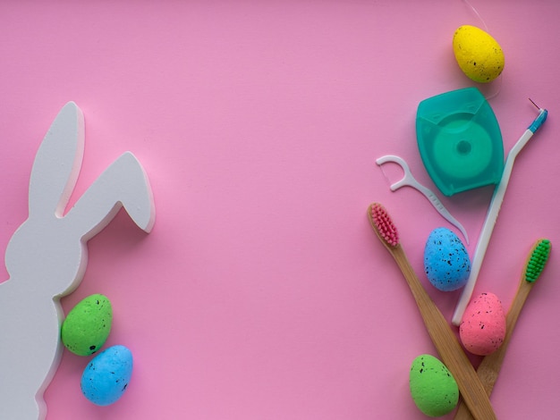 Wooden toothbrushes with Easter decorations on pink background