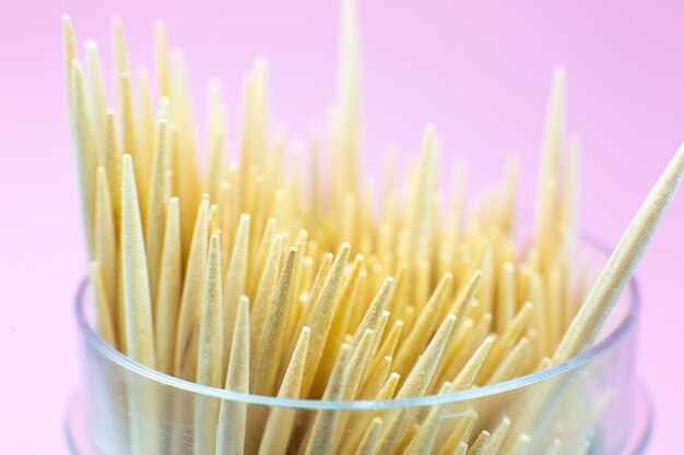 Wooden toothpicks macro photo. Close up, pink background.