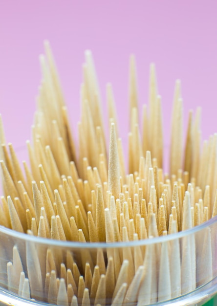 Wooden toothpicks macro photo. Close up, pink background.