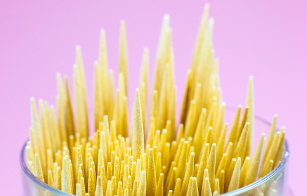 Wooden toothpicks macro photo. Close up, pink background.