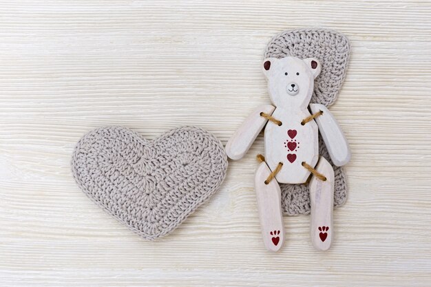 Wooden toy-bear with heart. White wooden bear on wood